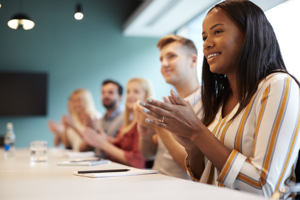 Group of young people sitting at a boardroom table smiling.