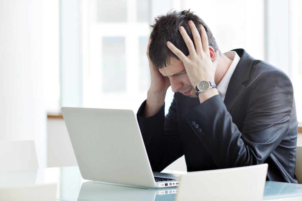 Frustrated man looking at his laptop reading a resume guide