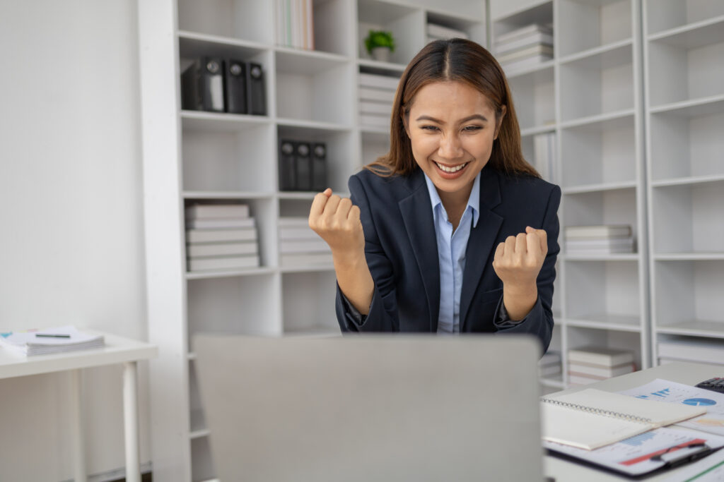 Business woman celebrating success on computer.