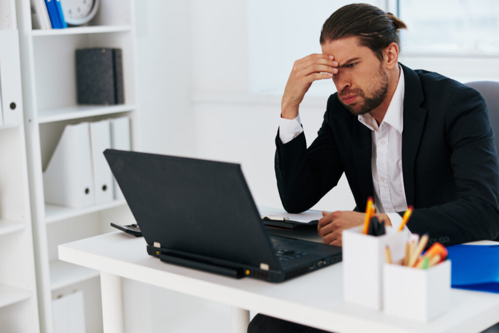 Frustrated business man on laptop trying to find a cover letter writing service.