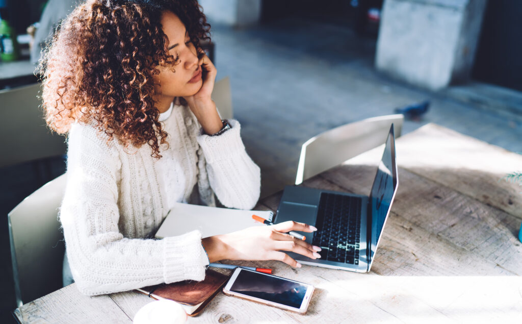 Thoughtful young woman looking at laptop