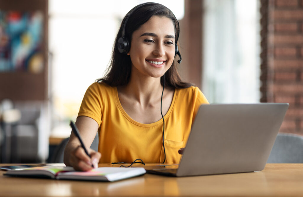 A woman diligently working on her laptop to hire a resume writer.