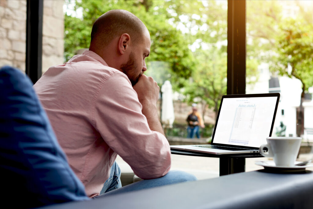 Man thoughtfully considering a job offer while looking at his computer.