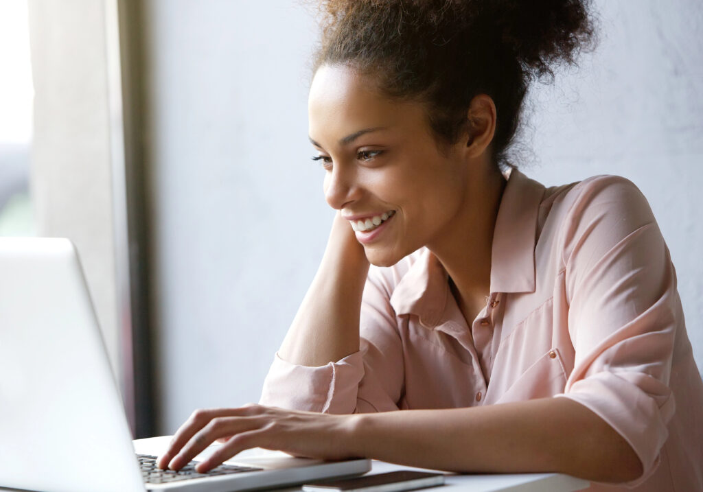 Woman smiling while on laptop after reading a job offer letter.